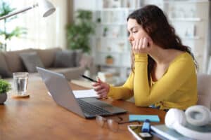 A woman at a desk distracted when she should be studying.